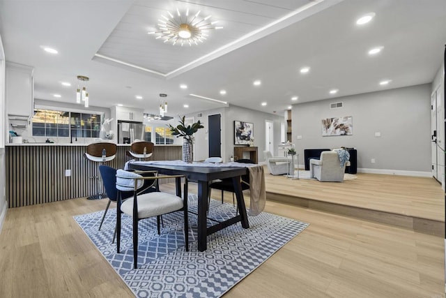 dining area featuring light wood-type flooring and a tray ceiling