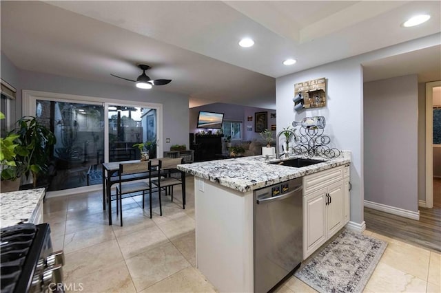 kitchen with sink, light stone counters, dishwasher, ceiling fan, and white cabinets