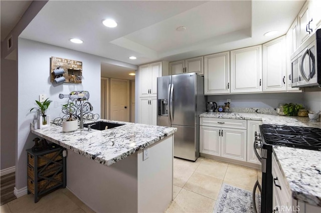 kitchen with a breakfast bar area, light tile patterned floors, stainless steel appliances, light stone countertops, and white cabinets