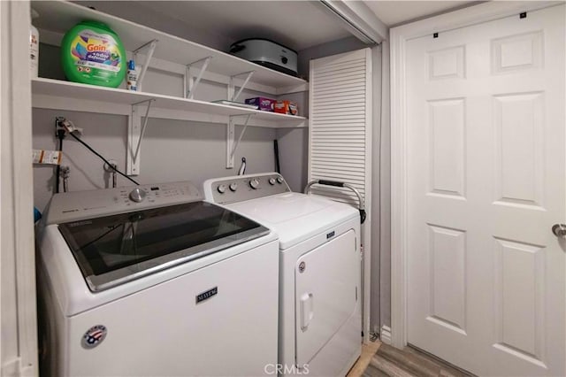 laundry area featuring washing machine and dryer and light hardwood / wood-style flooring