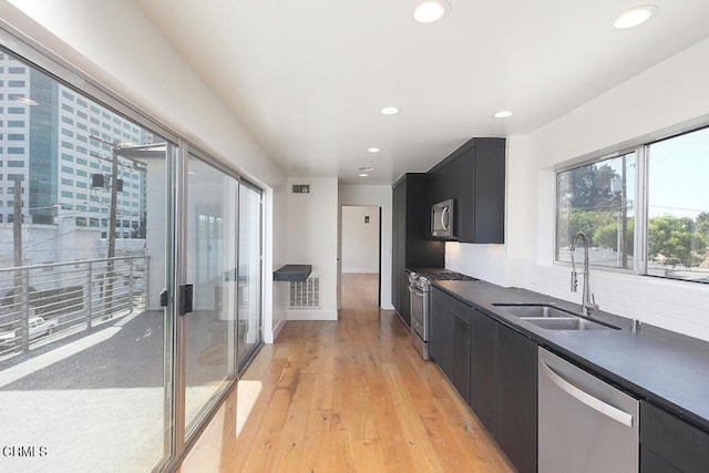 kitchen featuring tasteful backsplash, appliances with stainless steel finishes, sink, and light hardwood / wood-style floors