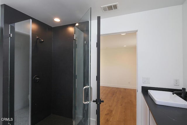 bathroom featuring hardwood / wood-style flooring, vanity, and a shower with shower door