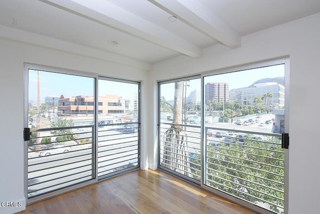 spare room with beam ceiling and hardwood / wood-style flooring