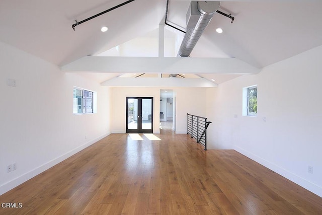 unfurnished room featuring hardwood / wood-style flooring, vaulted ceiling, a healthy amount of sunlight, and french doors