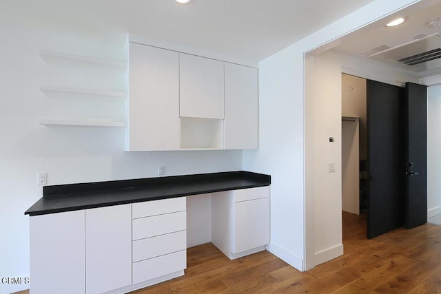 kitchen featuring white cabinetry, built in desk, and hardwood / wood-style flooring