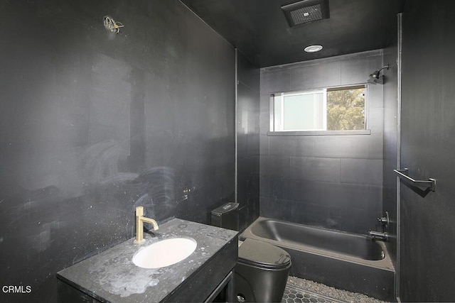 full bathroom with tiled shower / bath, vanity, and toilet