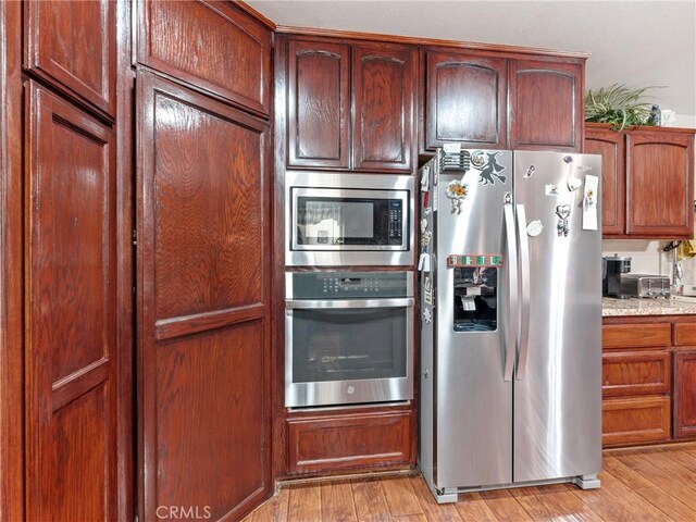 kitchen featuring light hardwood / wood-style flooring, light stone countertops, and appliances with stainless steel finishes