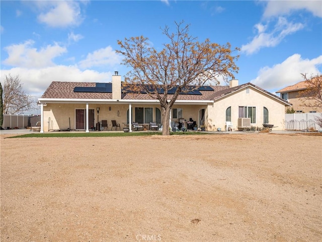 back of property with a patio and solar panels