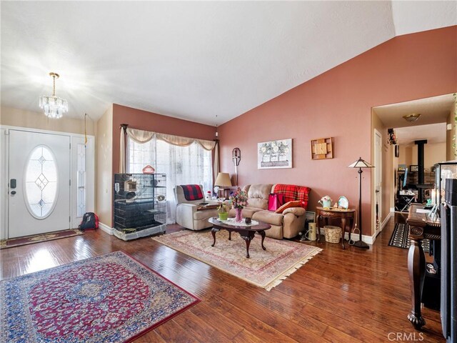 living room featuring an inviting chandelier, lofted ceiling, dark hardwood / wood-style floors, and a wood stove