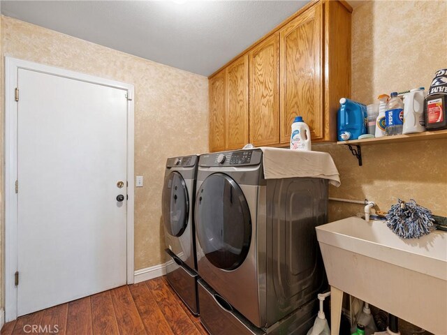 laundry room with dark hardwood / wood-style flooring, sink, cabinets, and washing machine and clothes dryer