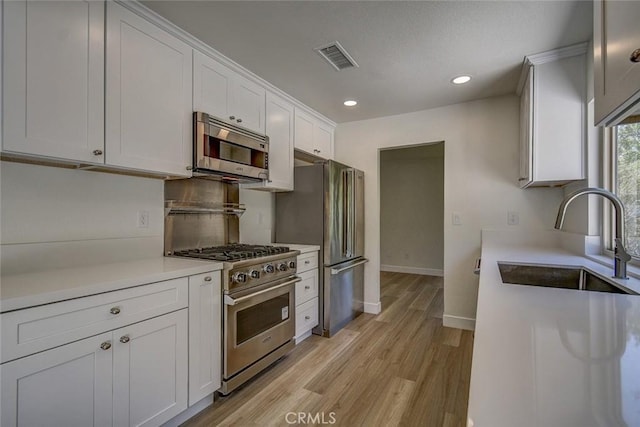 kitchen with stainless steel appliances, sink, and white cabinets