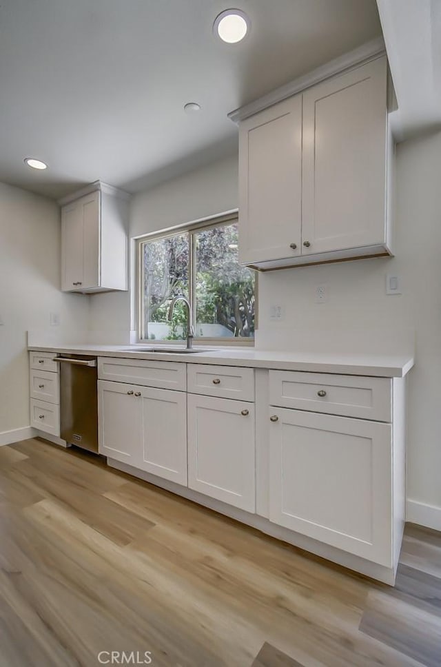 kitchen featuring dishwasher, sink, and white cabinets