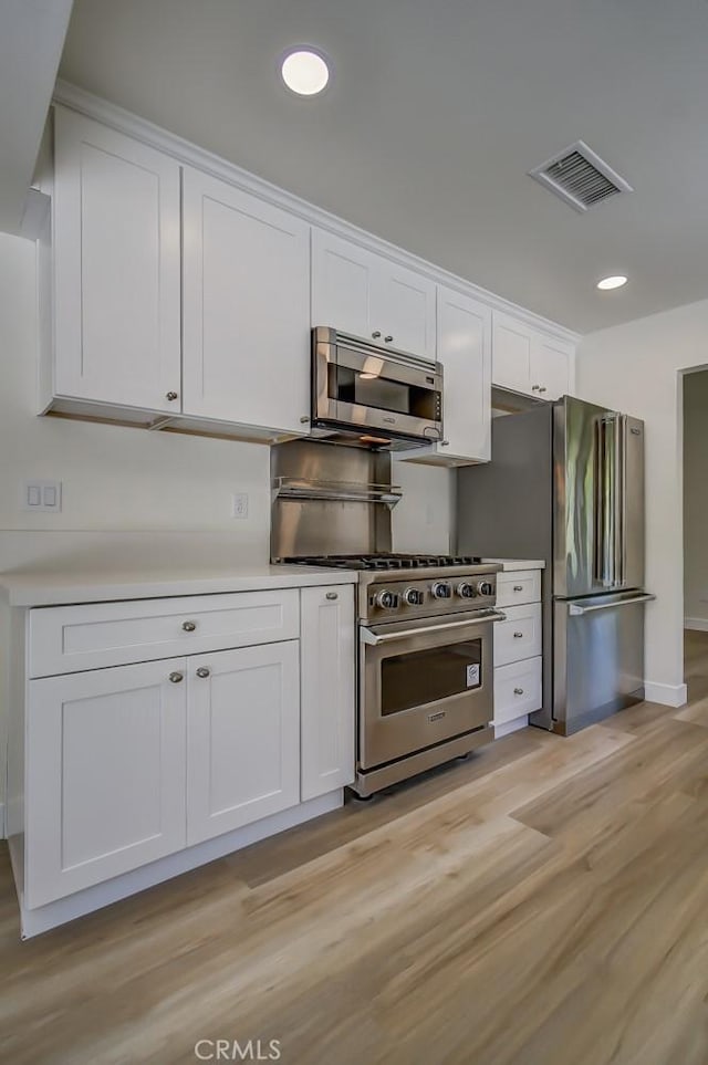 kitchen with white cabinetry, appliances with stainless steel finishes, and light hardwood / wood-style floors