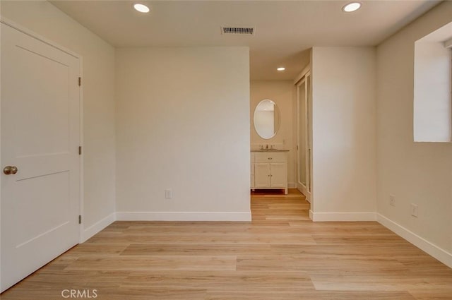 unfurnished bedroom with connected bathroom, sink, and light wood-type flooring