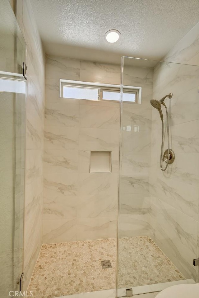 bathroom with a shower with door and a textured ceiling