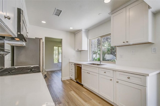 kitchen featuring white cabinetry, sink, light hardwood / wood-style floors, and appliances with stainless steel finishes