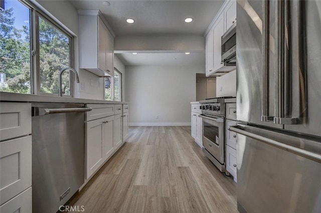 kitchen with high quality appliances, white cabinets, and light hardwood / wood-style flooring