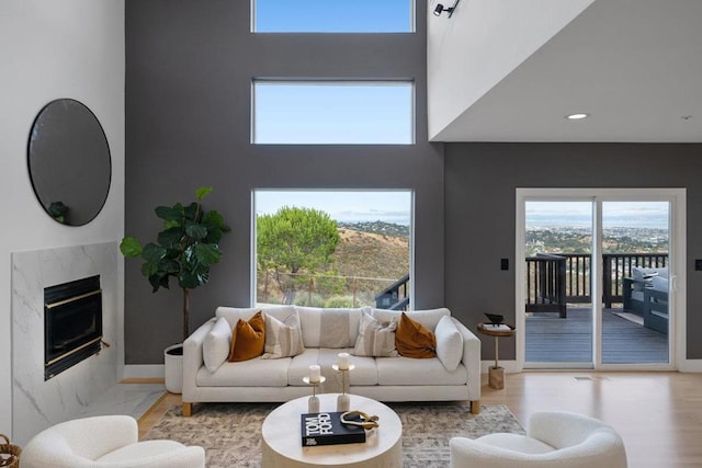 living room with a towering ceiling, a fireplace, and light wood-type flooring