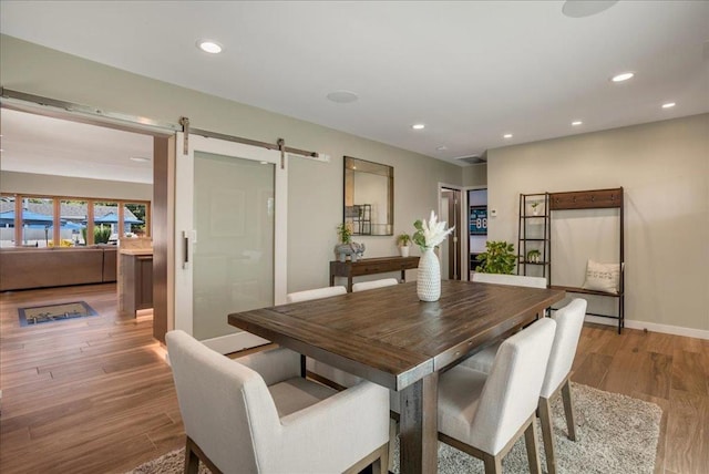 dining area with a barn door and light hardwood / wood-style floors