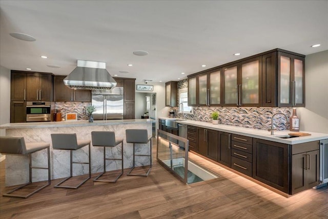 kitchen featuring appliances with stainless steel finishes, sink, a kitchen breakfast bar, dark brown cabinetry, and light wood-type flooring