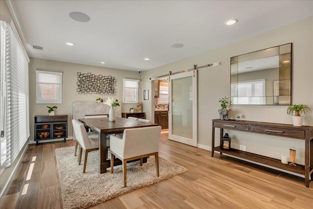 dining space with a barn door and light hardwood / wood-style floors