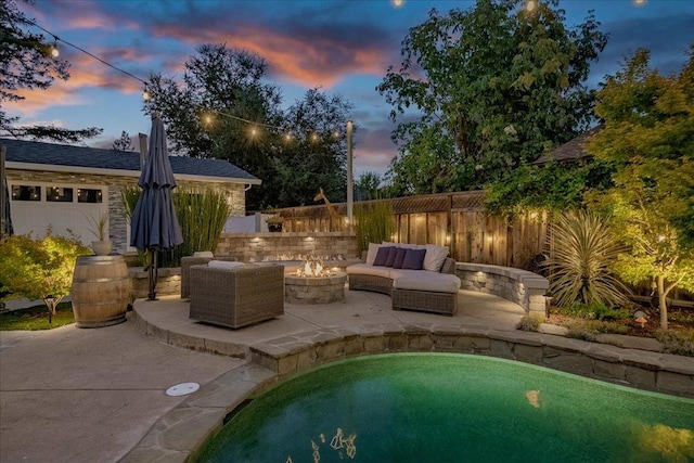 pool at dusk with an outdoor living space with a fire pit and a patio