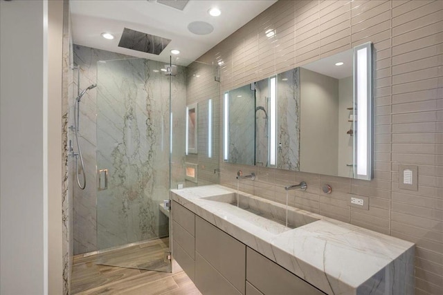 bathroom with sink, hardwood / wood-style flooring, tile walls, tasteful backsplash, and an enclosed shower