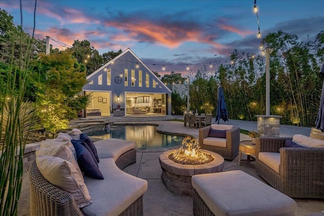 pool at dusk featuring a patio area and an outdoor living space with a fire pit