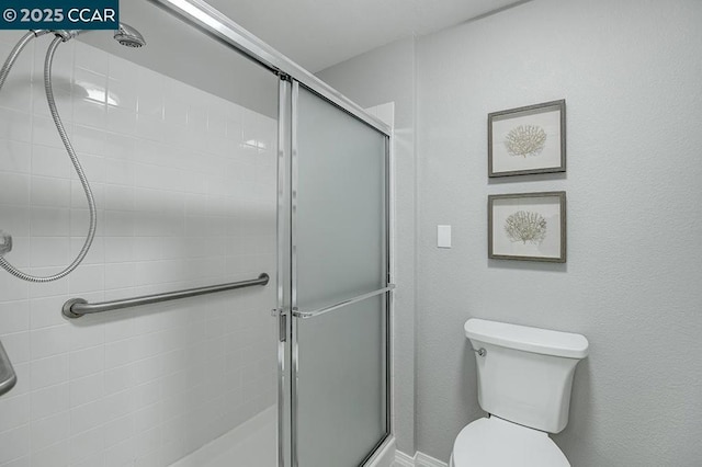 bathroom with a shower with door and toilet