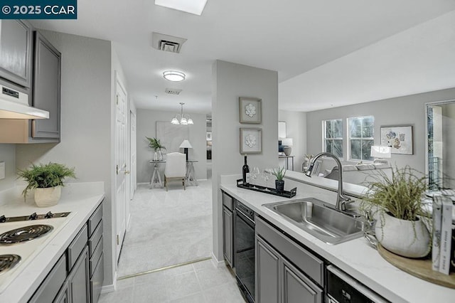 kitchen featuring light colored carpet, white cooktop, sink, and gray cabinetry