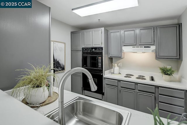 kitchen featuring gray cabinets, white cooktop, sink, and double oven