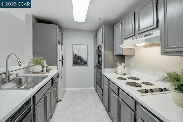 kitchen with gray cabinetry, sink, light stone counters, and black appliances