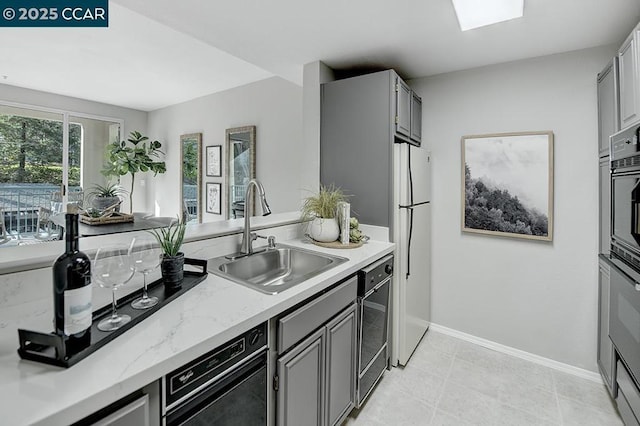 kitchen with gray cabinetry, sink, and white refrigerator