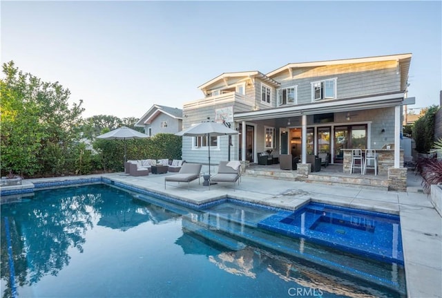 rear view of property with a swimming pool with hot tub, an outdoor hangout area, and a patio