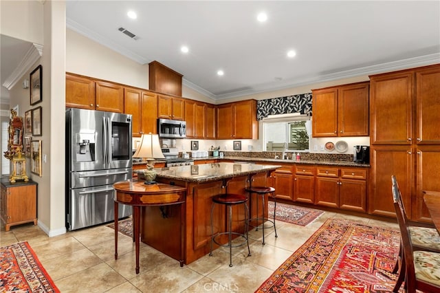 kitchen with sink, a breakfast bar area, dark stone counters, a center island, and stainless steel appliances