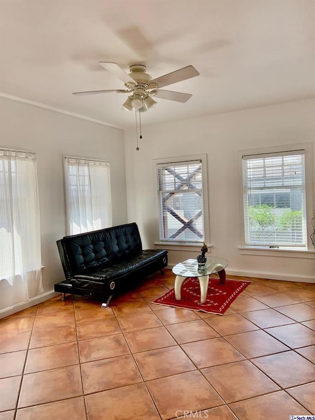 tiled living room featuring ceiling fan and baseboards