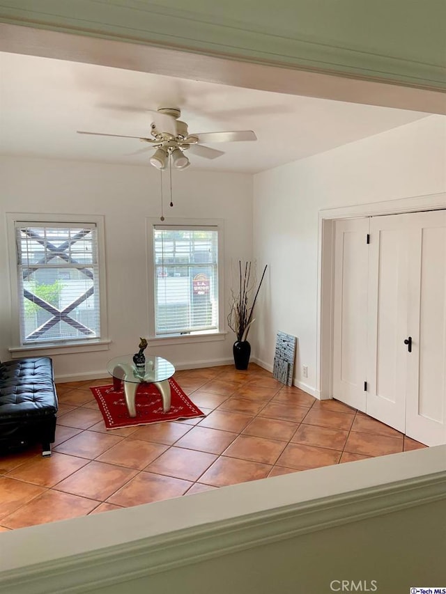 interior space featuring light tile patterned floors, ceiling fan, and baseboards