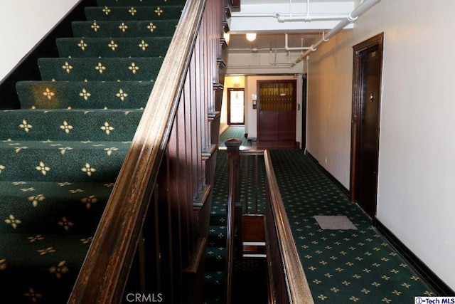 hall featuring stairs, baseboards, and carpet flooring