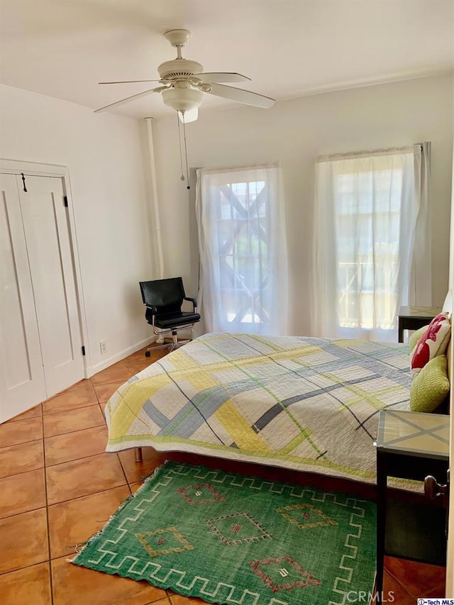 bedroom with light tile patterned floors, ceiling fan, and baseboards