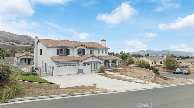 mediterranean / spanish-style house featuring driveway, a garage, a chimney, a tiled roof, and a mountain view