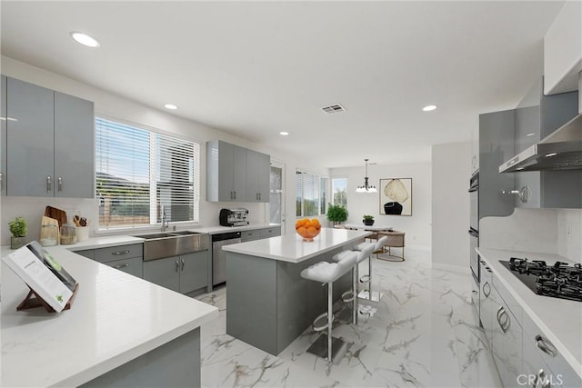 kitchen with a kitchen bar, a center island, and gray cabinetry