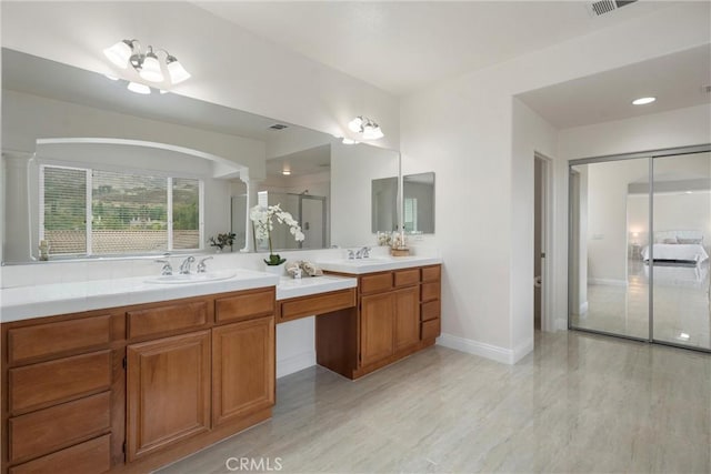 bathroom featuring vanity, a shower with shower door, and decorative columns