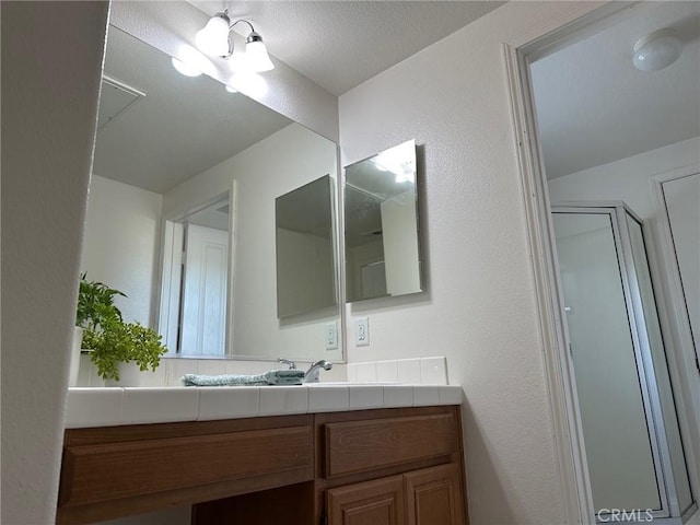 bathroom with walk in shower and vanity