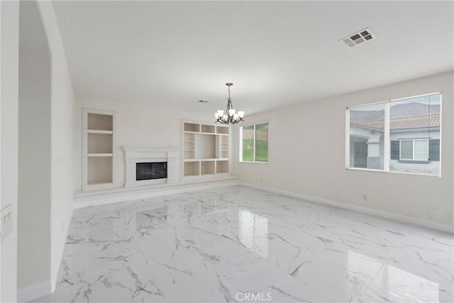 unfurnished living room with an inviting chandelier and built in shelves