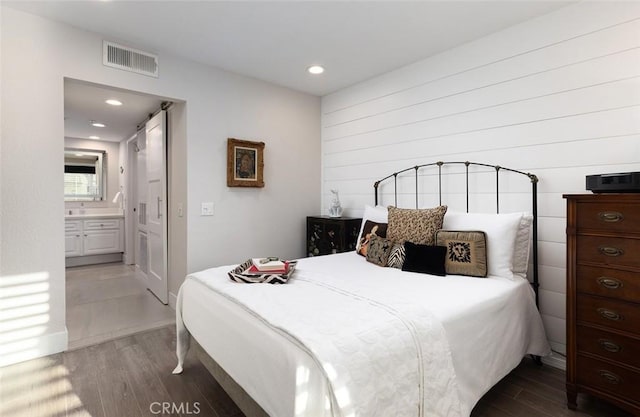 bedroom with connected bathroom and dark hardwood / wood-style flooring