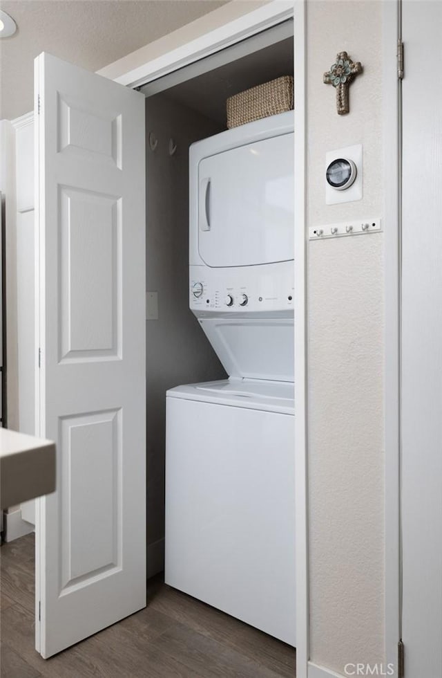 clothes washing area featuring dark hardwood / wood-style flooring and stacked washer / dryer