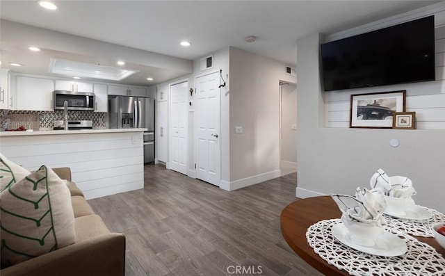 living room with wood-type flooring and a tray ceiling