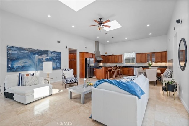 living room with sink, a skylight, ceiling fan, and a high ceiling