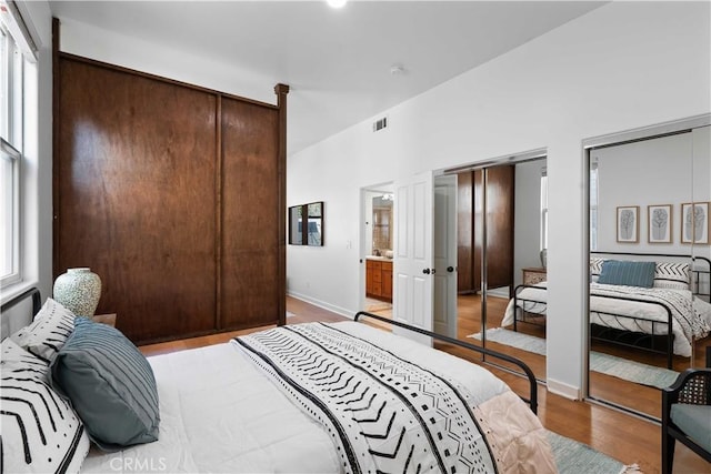 bedroom with two closets and light wood-type flooring