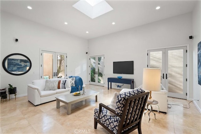 living room featuring french doors, a towering ceiling, and a skylight